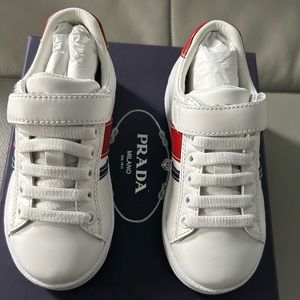 All white Prada sneakers with Red and White Stripes. Toddler size US 8.5/EU 24
